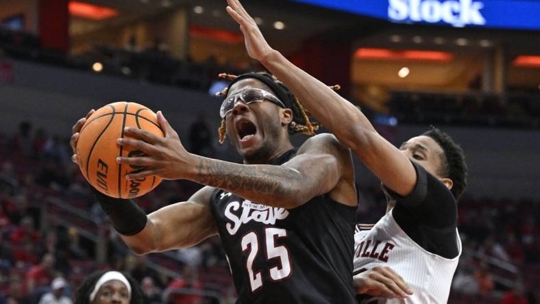 Nov 26, 2023; Louisville, Kentucky, USA; New Mexico State Aggies forward Clarence Jackson (25) attempts to shoot against Louisville Cardinals forward JJ Traynor (12) during the first half at KFC Yum! Center. Mandatory Credit: Jamie Rhodes-USA TODAY Sports