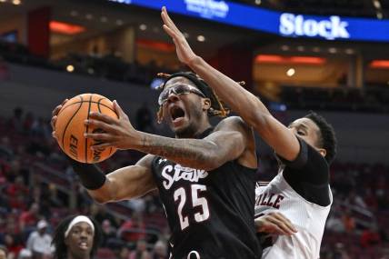Nov 26, 2023; Louisville, Kentucky, USA; New Mexico State Aggies forward Clarence Jackson (25) attempts to shoot against Louisville Cardinals forward JJ Traynor (12) during the first half at KFC Yum! Center. Mandatory Credit: Jamie Rhodes-USA TODAY Sports