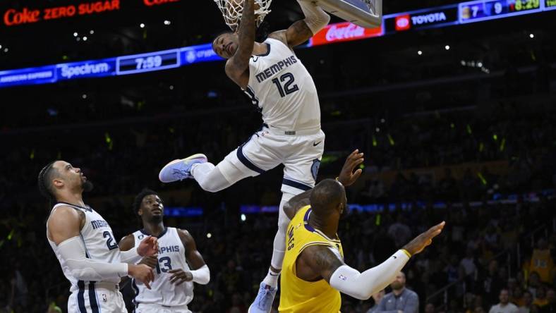 Apr 28, 2023; Los Angeles, California, USA; Memphis Grizzlies guard Ja Morant (12) hangs on the rim to avoid landing on Los Angeles Lakers forward LeBron James (6) after a dunk in the first quarter of game six of the 2023 NBA playoffs at Crypto.com Arena. Mandatory Credit: Jayne Kamin-Oncea-USA TODAY Sports