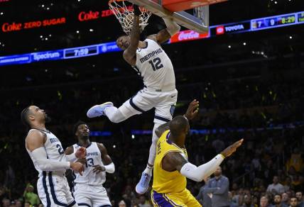 Apr 28, 2023; Los Angeles, California, USA; Memphis Grizzlies guard Ja Morant (12) hangs on the rim to avoid landing on Los Angeles Lakers forward LeBron James (6) after a dunk in the first quarter of game six of the 2023 NBA playoffs at Crypto.com Arena. Mandatory Credit: Jayne Kamin-Oncea-USA TODAY Sports