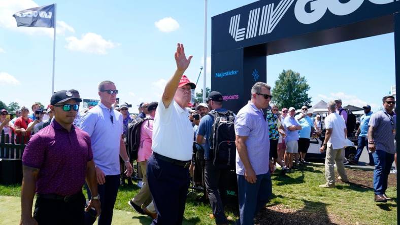 Former President Donald Trump waves to the crowd as he exits the putting green with his aide Walt Nauta, left, during the final round of the LIV Golf Bedminster golf tournament at Trump National Bedminster on Sunday, Aug. 13, 2023.