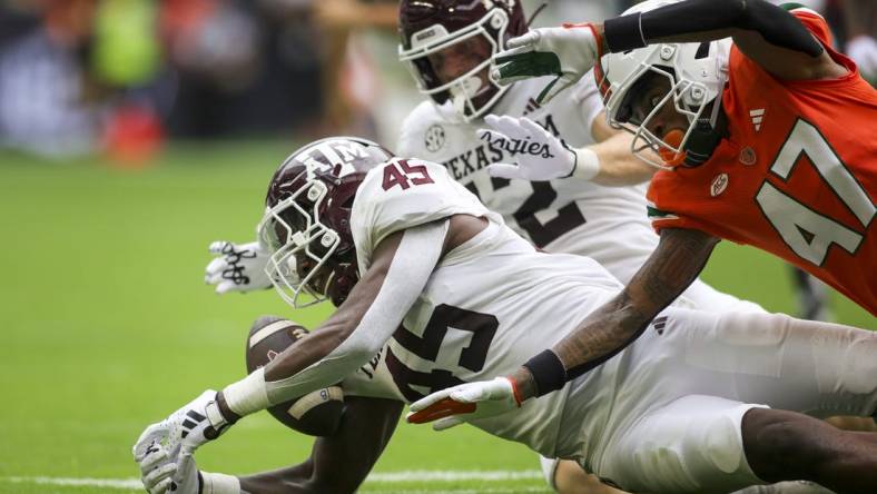 Aggies linebacker Edgerrin Cooper (45) recovers a fumble against the Miami Hurricanes during the second quarter at Hard Rock Stadium. Mandatory Credit: Sam Navarro-USA TODAY Sports