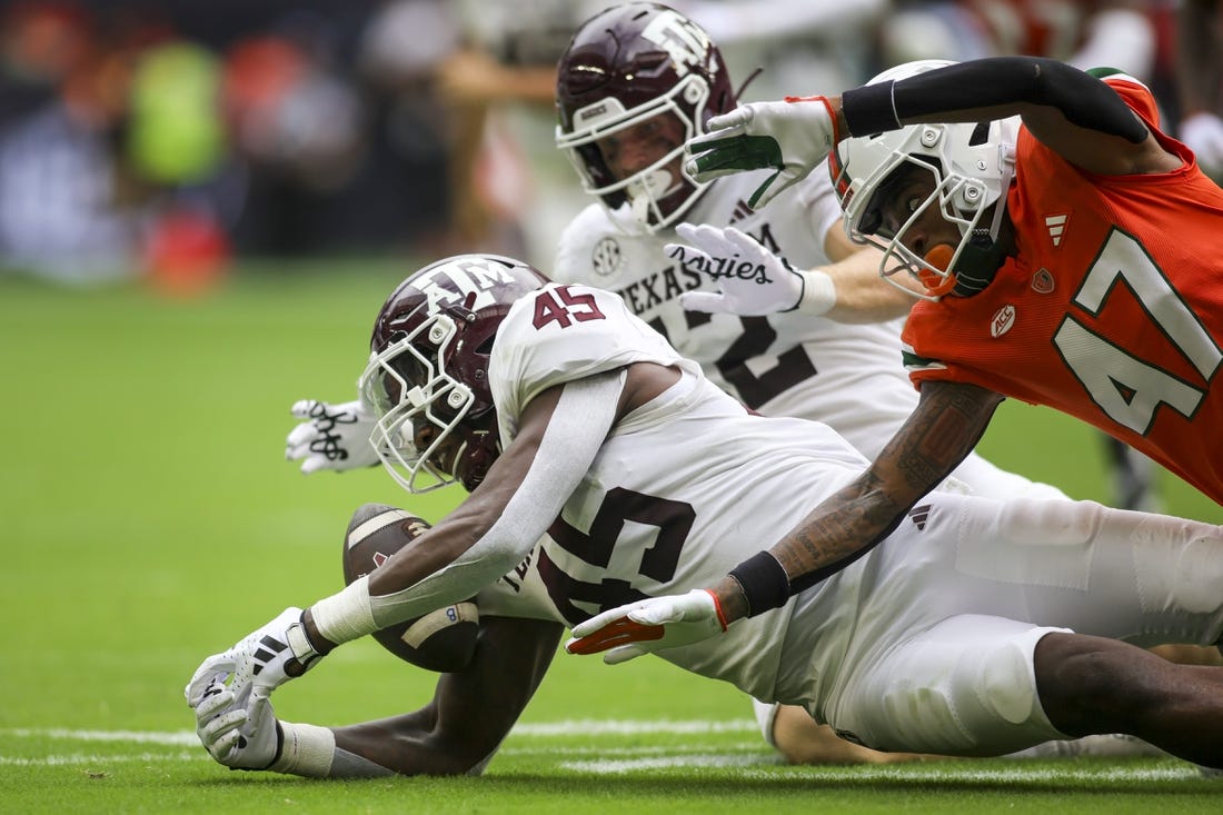 Aggies linebacker Edgerrin Cooper (45) recovers a fumble against the Miami Hurricanes during the second quarter at Hard Rock Stadium. Mandatory Credit: Sam Navarro-USA TODAY Sports