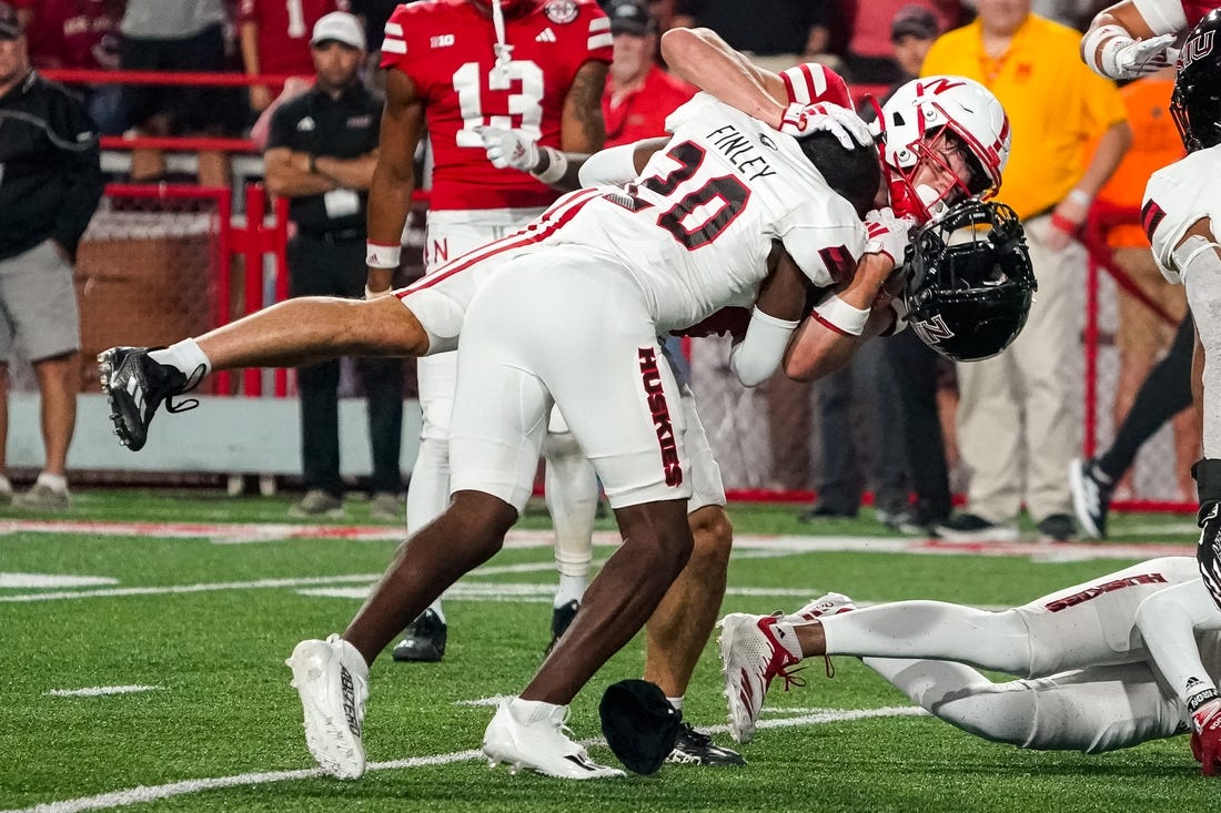 Sep 16, 2023; Lincoln, Nebraska, USA; Northern Illinois Huskies cornerback Jacob Finley (20) loses his helmet while tackling Nebraska Cornhuskers wide receiver Alex Bullock (84) during the third quarter at Memorial Stadium. Mandatory Credit: Dylan Widger-USA TODAY Sports