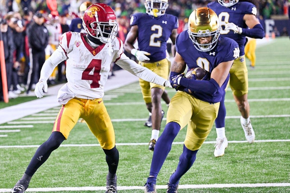 Oct 14, 2023; South Bend, Indiana, USA; Notre Dame Fighting Irish safety Xavier Watts (0) scores a touchdown in front of USC Trojans wide receiver Mario Williams (4) after a fumble recovery in the fourth quarter at Notre Dame Stadium. Notre Dame won 48-20. Mandatory Credit: Matt Cashore-USA TODAY Sports