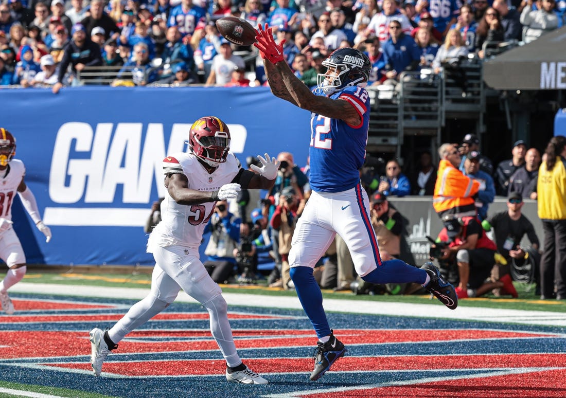 Oct 22, 2023; East Rutherford, New Jersey, USA; New York Giants tight end Darren Waller (12) catches a touchdown pass during the first half in front of Washington Commanders linebacker Cody Barton (57) at MetLife Stadium. Mandatory Credit: Vincent Carchietta-USA TODAY Sports