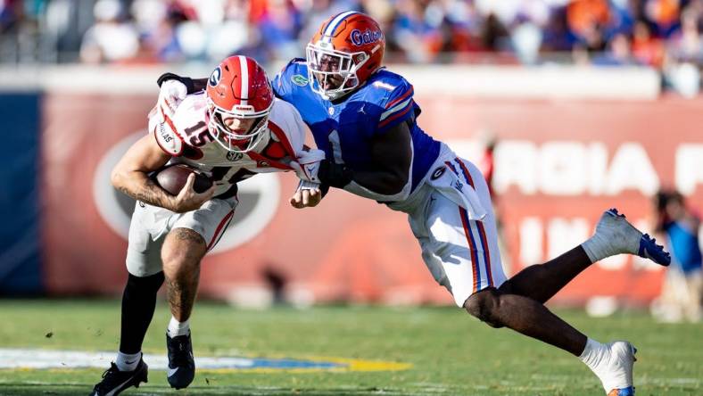 Florida Gators defensive end Princely Umanmielen (1) tackles Georgia Bulldogs quarterback Carson Beck (15) during the first half at Everbank Stadium in Jacksonville, FL on Saturday, October 28, 2023. [Matt Pendleton/Gainesville Sun]