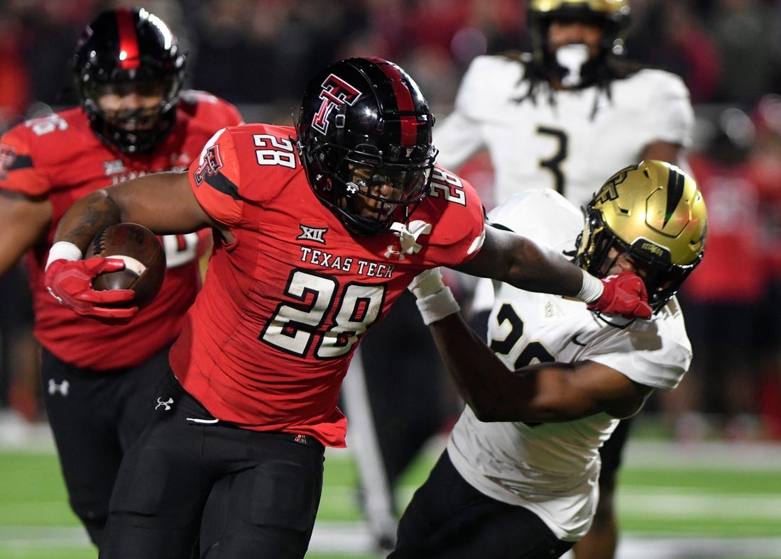 Texas Tech's running back Tahj Brooks (28) stiff-arms UCF's defensive back William Wells (29) during the Big 12 football game, Saturday, Nov. 18, 2023, at Jones AT&T Stadium.