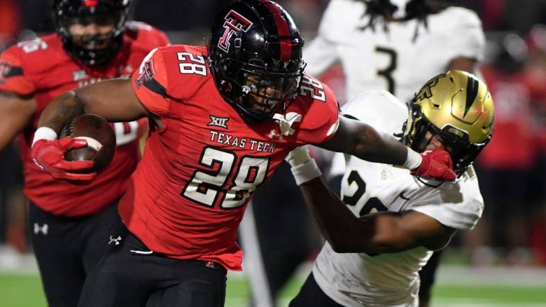 Texas Tech's running back Tahj Brooks (28) stiff-arms UCF's defensive back William Wells (29) during the Big 12 football game, Saturday, Nov. 18, 2023, at Jones AT&T Stadium.