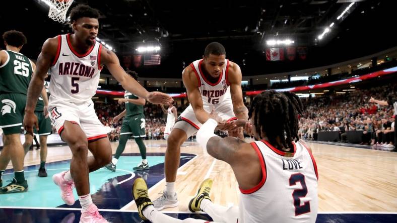 Arizona Wildcats guard KJ Lewis (5), left, and Arizona Wildcats forward Keshad Johnson (16) help Arizona Wildcats guard Caleb Love (2) to his feet during the Acrisure Classic.