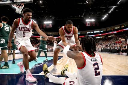 Arizona Wildcats guard KJ Lewis (5), left, and Arizona Wildcats forward Keshad Johnson (16) help Arizona Wildcats guard Caleb Love (2) to his feet during the Acrisure Classic.
