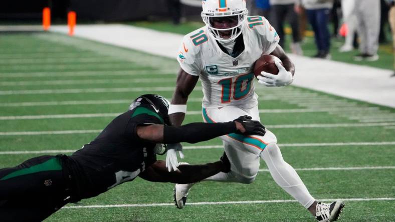 Nov 24, 2023; East Rutherford, New Jersey, USA; Miami Dolphins wide receiver Tyreek Hill (10) is tackled by New York Jets cornerback D.J. Reed (4) in the second half at MetLife Stadium. Mandatory Credit: Robert Deutsch-USA TODAY Sports