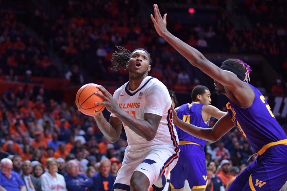 Nov 24, 2023; Champaign, Illinois, USA;  Illinois Fighting Illini forward Dain Dainja (42) drives to the basket as Western Illinois Leathernecks center Drew Cisse (23) defends during the first half at State Farm Center. Mandatory Credit: Ron Johnson-USA TODAY Sports