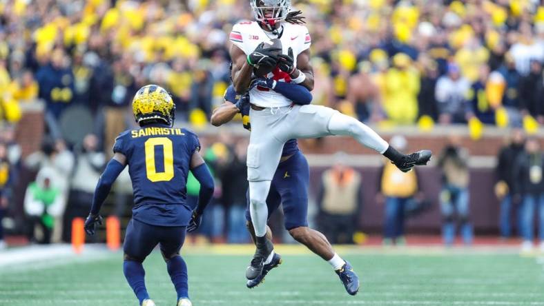 Ohio State wide receiver Marvin Harrison Jr. makes a catch against Michigan defensive backs Quinten Johnson and Mike Sainristil during the second half at Michigan Stadium in Ann Arbor on Saturday, Nov. 25, 2023.