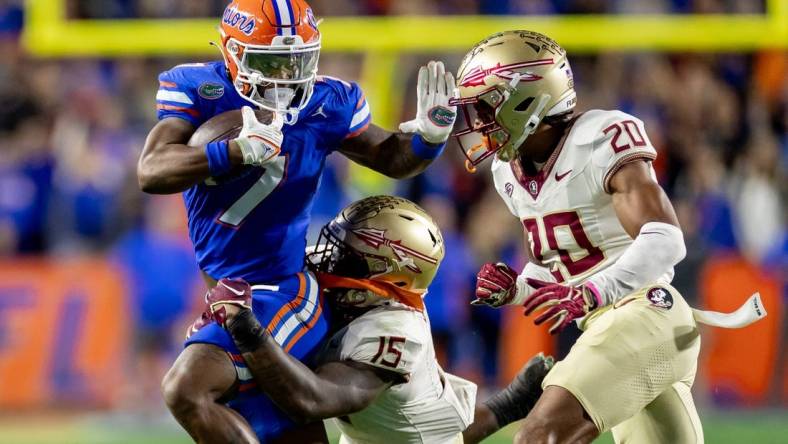 Florida Gators running back Trevor Etienne (7) rushes with the ball while Florida State Seminoles linebacker Tatum Bethune (15) and Florida State Seminoles defensive back Azareye'h Thomas (20) attempt to tackle during the first half at Steve Spurrier Field at Ben Hill Griffin Stadium in Gainesville, FL on Saturday, November 25, 2023. [Matt Pendleton/Gainesville Sun]