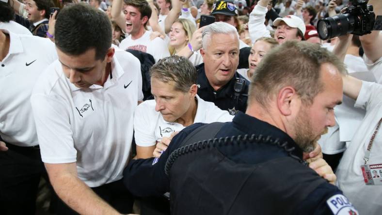 Nov 29, 2023; Fayetteville, Arkansas, USA; Arkansas Razorbacks head coach Eric Musselman is ushered off of the court by police after the game against the Duke Blue Devils at Bud Walton Arena. Arkansas won 80-75. Mandatory Credit: Nelson Chenault-USA TODAY Sports.