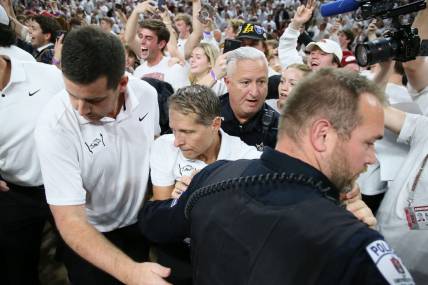 Nov 29, 2023; Fayetteville, Arkansas, USA; Arkansas Razorbacks head coach Eric Musselman is ushered off of the court by police after the game against the Duke Blue Devils at Bud Walton Arena. Arkansas won 80-75. Mandatory Credit: Nelson Chenault-USA TODAY Sports.