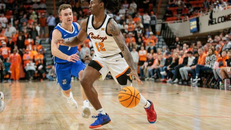 Nov 30, 2023; Stillwater, Oklahoma, USA; Oklahoma State Cowboys guard Javon Small (12) drives to the basket around Creighton Bluejays guard Steven Ashworth (1) during the first half at Gallagher-Iba Arena. Mandatory Credit: William Purnell-USA TODAY Sports