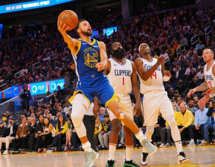 Nov 30, 2023; San Francisco, California, USA; Golden State Warriors guard Stephen Curry (30) scores against Los Angeles Clippers guard James Harden (1), guard Terance Mann (14) during the fourth quarter at Chase Center. Mandatory Credit: Kelley L Cox-USA TODAY Sports