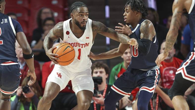 Dec 9, 2023; Houston, Texas, USA; Houston Cougars guard Jamal Shead (1) controls the ball as Jackson State Tigers guard Chase Adams (10) defends during the first half at Fertitta Center. Mandatory Credit: Troy Taormina-USA TODAY Sports