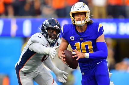 Dec 10, 2023; Inglewood, California, USA; Los Angeles Chargers quarterback Justin Herbert (10) moves out to pass against the defense of Denver Broncos linebacker Jonathon Cooper (0) during the first half at SoFi Stadium. Mandatory Credit: Gary A. Vasquez-USA TODAY Sports
