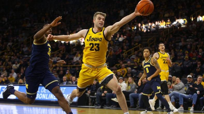 Iowa   s Ben Krikke (23) reaches for a ball, attempting to keep it inbounds Sunday, Dec. 10, 2023 at Carver-Hawkeye Arena in Iowa City, Iowa.