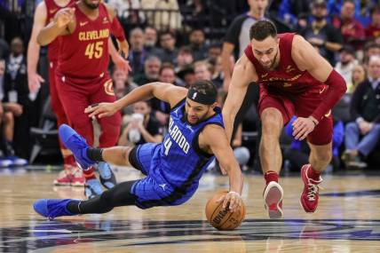Dec 11, 2023; Orlando, Florida, USA; Orlando Magic guard Jalen Suggs (4) and Cleveland Cavaliers guard Max Strus (1) chase a loose ball during the second quarter at Amway Center. Mandatory Credit: Mike Watters-USA TODAY Sports