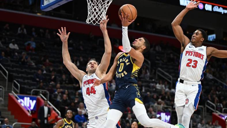 Dec 11, 2023; Detroit, Michigan, USA;  Indiana Pacers guard Tyrese Haliburton (0) drives to the basket against Detroit Pistons forward Bojan Bogdanovic (44) and Pistons guard Jaden Ivey (23) in the second quarter at Little Caesars Arena. Mandatory Credit: Lon Horwedel-USA TODAY Sports