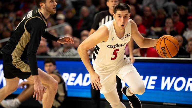 Cincinnati Bearcats guard CJ Fredrick (5) drives passed Bryant Bulldogs forward Connor Withers (7) in the first half of the NCAA Basketball game between the Bryant Bulldogs and Cincinnati Bearcats at Fifth Third Arena in Cincinnati on Tuesday, Dec. 12, 2023.