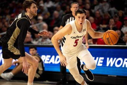 Cincinnati Bearcats guard CJ Fredrick (5) drives passed Bryant Bulldogs forward Connor Withers (7) in the first half of the NCAA Basketball game between the Bryant Bulldogs and Cincinnati Bearcats at Fifth Third Arena in Cincinnati on Tuesday, Dec. 12, 2023.
