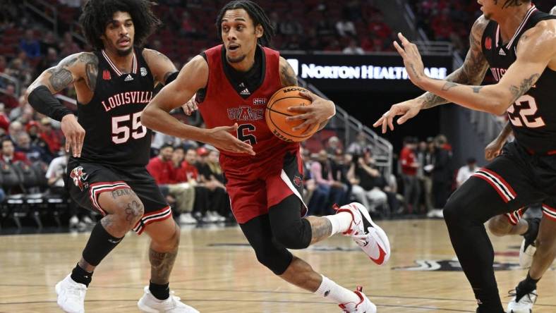 Dec 13, 2023; Louisville, Kentucky, USA; Arkansas State Red Wolves guard Taryn Todd (6) drives to the basket against Louisville Cardinals guard Skyy Clark (55) and  guard Tre White (22) during the first half at KFC Yum! Center. Mandatory Credit: Jamie Rhodes-USA TODAY Sports