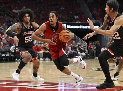 Dec 13, 2023; Louisville, Kentucky, USA; Arkansas State Red Wolves guard Taryn Todd (6) drives to the basket against Louisville Cardinals guard Skyy Clark (55) and  guard Tre White (22) during the first half at KFC Yum! Center. Mandatory Credit: Jamie Rhodes-USA TODAY Sports