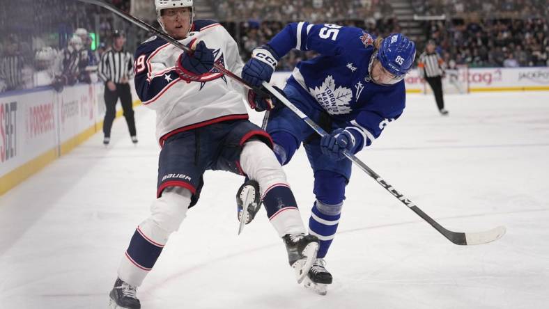 Dec 14, 2023; Toronto, Ontario, CAN; Toronto Maple Leafs defenseman William Lagesson (85) upends Columbus Blue Jackets forward Patrik Laine (29) as they go to the boards during the second period at Scotiabank Arena. Mandatory Credit: John E. Sokolowski-USA TODAY Sports