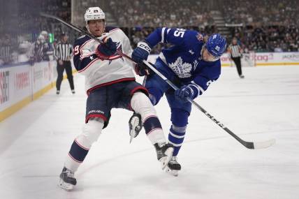 Dec 14, 2023; Toronto, Ontario, CAN; Toronto Maple Leafs defenseman William Lagesson (85) upends Columbus Blue Jackets forward Patrik Laine (29) as they go to the boards during the second period at Scotiabank Arena. Mandatory Credit: John E. Sokolowski-USA TODAY Sports