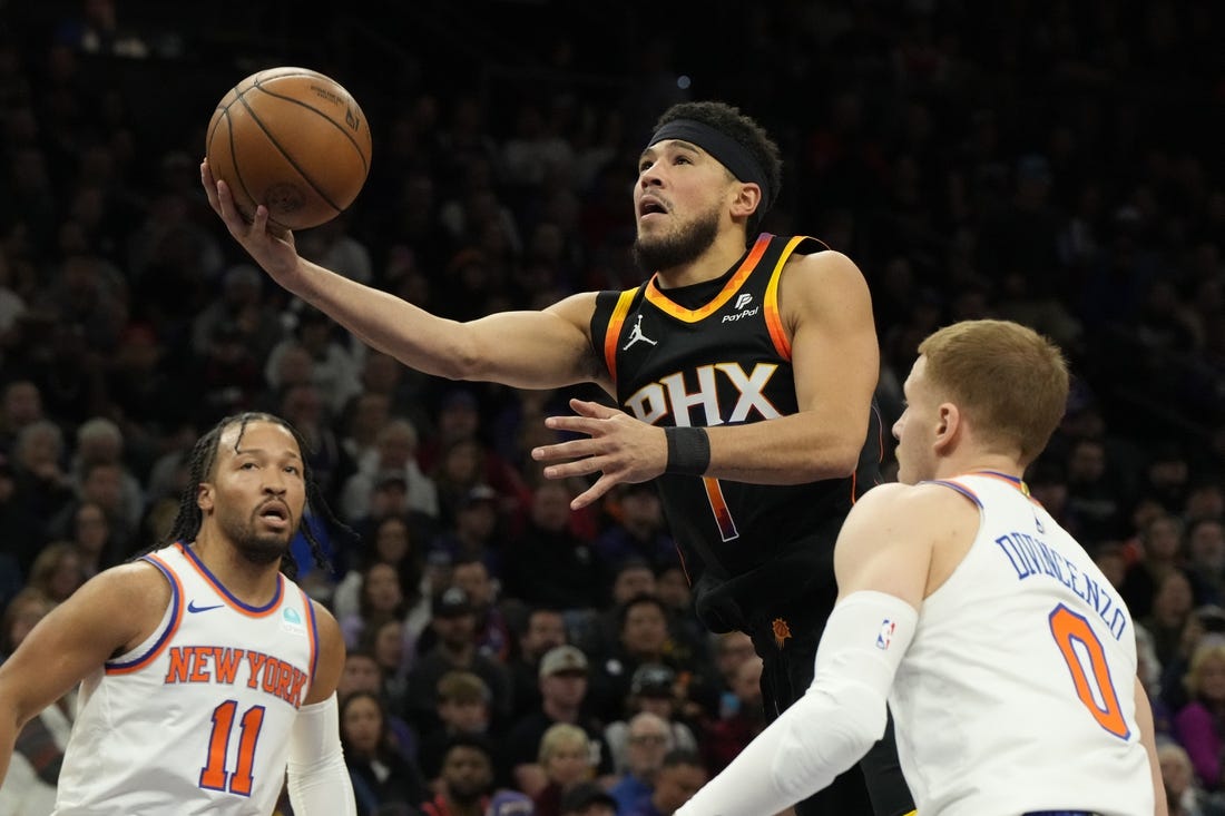 Dec 15, 2023; Phoenix, Arizona, USA; Phoenix Suns guard Devin Booker (1) drives between New York Knicks guard Jalen Brunson (11) and  guard Donte DiVincenzo (0) in the first half at Footprint Center. Mandatory Credit: Rick Scuteri-USA TODAY Sports