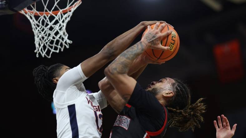 Dec 16, 2023; Charlottesville, Virginia, USA; Virginia Cavaliers guard Elijah Gertrude (12) blocks the shot of Northeastern Huskies guard Joe Pridgen (0) in the first half at John Paul Jones Arena. Mandatory Credit: Geoff Burke-USA TODAY Sports