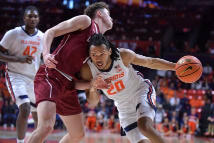 Dec 17, 2023; Champaign, Illinois, USA;  Illinois Fighting Illini forward Ty Rodgers (20) drives the ball against Colgate Raiders guard Brady Cummins (1) during the first half at State Farm Center. Mandatory Credit: Ron Johnson-USA TODAY Sports