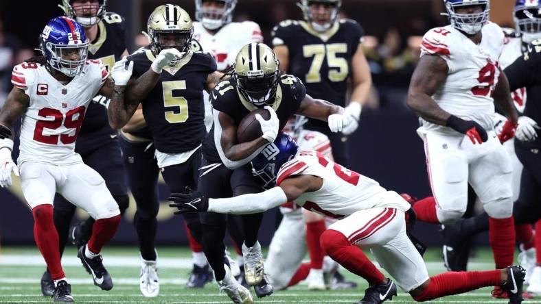 Dec 17, 2023; New Orleans, Louisiana, USA; New Orleans Saints running back Alvin Kamara (41) is tackled by New York Giants safety Jason Pinnock (27) during the second half at Caesars Superdome. Mandatory Credit: Stephen Lew-USA TODAY Sports