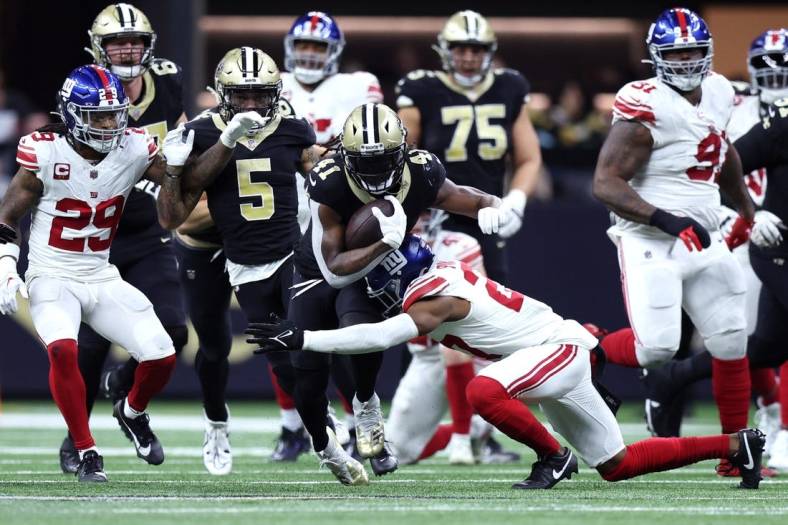 Dec 17, 2023; New Orleans, Louisiana, USA; New Orleans Saints running back Alvin Kamara (41) is tackled by New York Giants safety Jason Pinnock (27) during the second half at Caesars Superdome. Mandatory Credit: Stephen Lew-USA TODAY Sports
