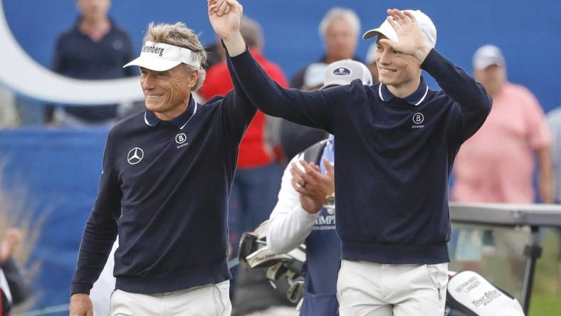 Dec 17, 2023; Orlando, Florida, USA;  Bernhard Langer (left) and his son Jason Langer react to the crowd after they are announced walking onto the 18th green at the PNC Championship at The Ritz-Carlton Golf Club. Mandatory Credit: Reinhold Matay-USA TODAY Sports