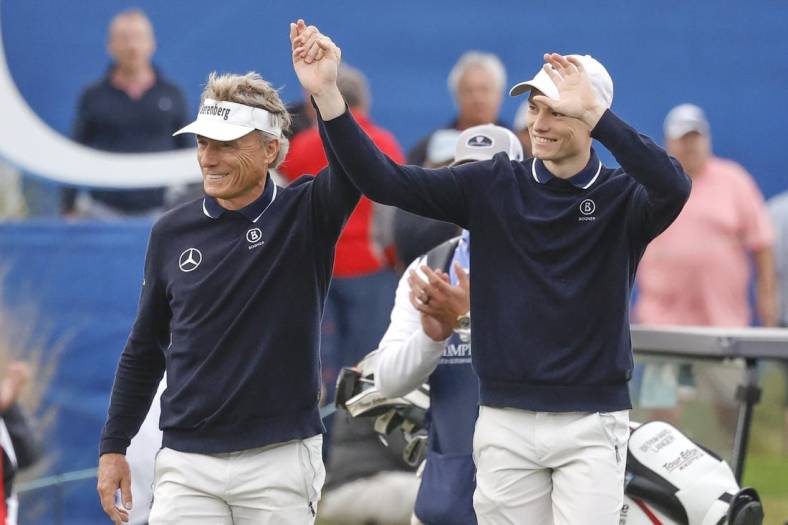 Dec 17, 2023; Orlando, Florida, USA;  Bernhard Langer (left) and his son Jason Langer react to the crowd after they are announced walking onto the 18th green at the PNC Championship at The Ritz-Carlton Golf Club. Mandatory Credit: Reinhold Matay-USA TODAY Sports