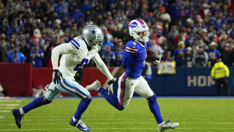 Dec 17, 2023; Orchard Park, New York, USA; Buffalo Bills running back James Cook (4) runs the ball pressured by Dallas Cowboys cornerback Jourdan Lewis (2) in the first half at Highmark Stadium. Mandatory Credit: Gregory Fisher-USA TODAY Sports