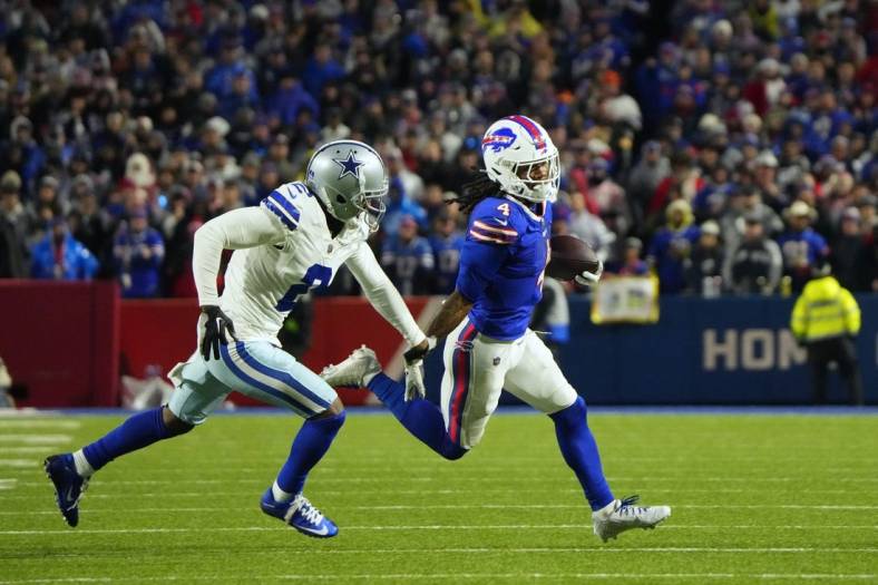 Dec 17, 2023; Orchard Park, New York, USA; Buffalo Bills running back James Cook (4) runs the ball pressured by Dallas Cowboys cornerback Jourdan Lewis (2) in the first half at Highmark Stadium. Mandatory Credit: Gregory Fisher-USA TODAY Sports