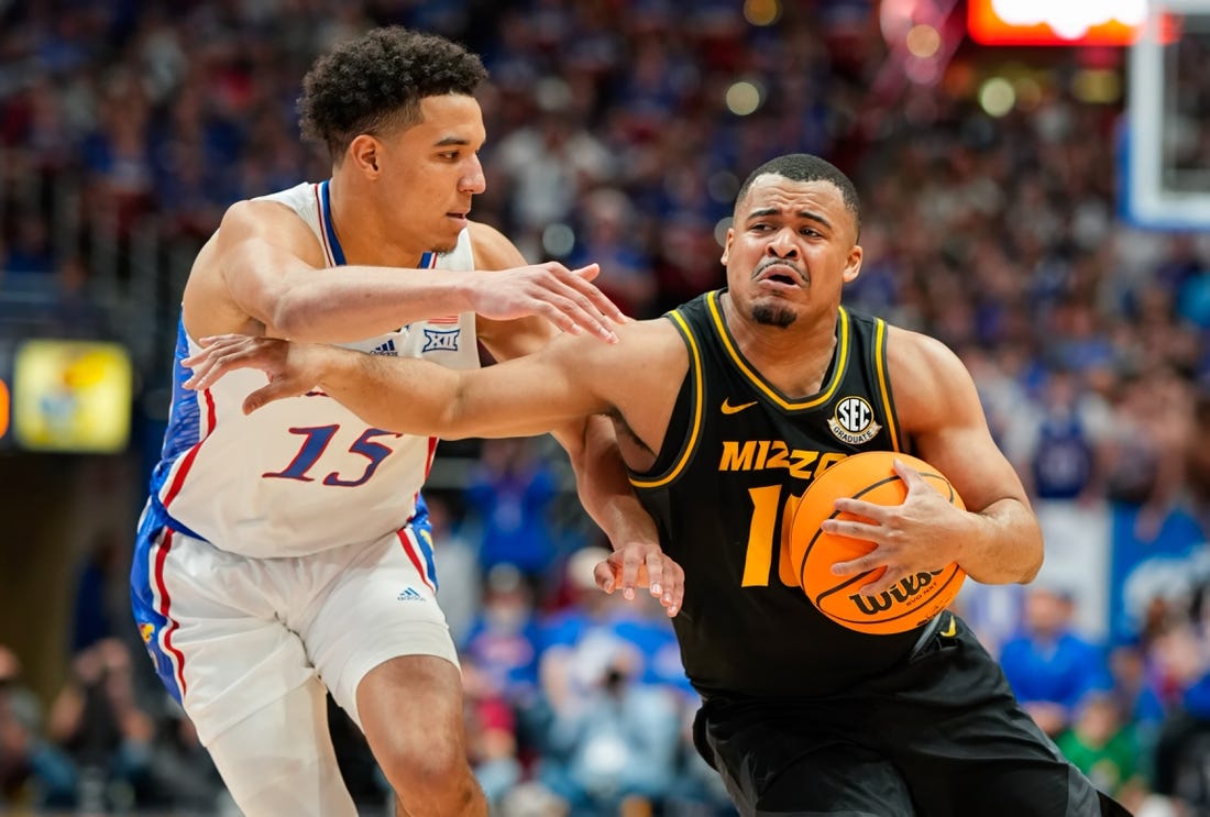 Dec 9, 2023; Lawrence, Kansas, USA; Missouri Tigers guard Nick Honor (10) drives against Kansas Jayhawks guard Kevin McCullar Jr. (15) during the first half at Allen Fieldhouse. Mandatory Credit: Jay Biggerstaff-USA TODAY Sports