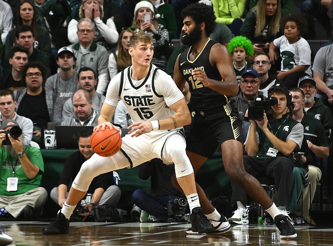 Dec 18, 2023; East Lansing, Michigan, USA;   Michigan State Spartans center Carson Cooper (15) dribbles the ball against Oakland Golden Grizzlies forward Tuburu Naivalurua (12) during the first half at Jack Breslin Student Events Center. Mandatory Credit: Dale Young-USA TODAY Sports