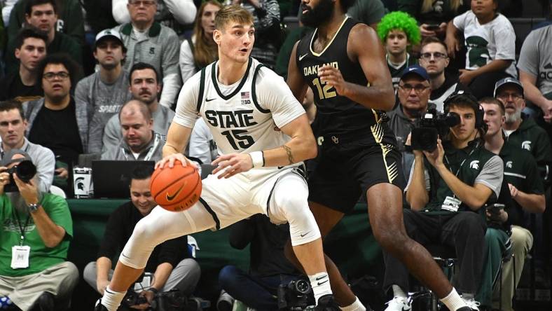 Dec 18, 2023; East Lansing, Michigan, USA;   Michigan State Spartans center Carson Cooper (15) dribbles the ball against Oakland Golden Grizzlies forward Tuburu Naivalurua (12) during the first half at Jack Breslin Student Events Center. Mandatory Credit: Dale Young-USA TODAY Sports