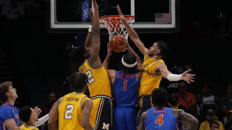 Dec 19, 2023; Charlotte, North Carolina, USA; Florida Gators guard Walter Clayton Jr. (1) is sandwiched at the basket by Michigan Wolverines forward Tarris Reed Jr. (32) and forward Olivier Nkamhoua (13) during the first half at Spectrum Center. Mandatory Credit: Jim Dedmon-USA TODAY Sports