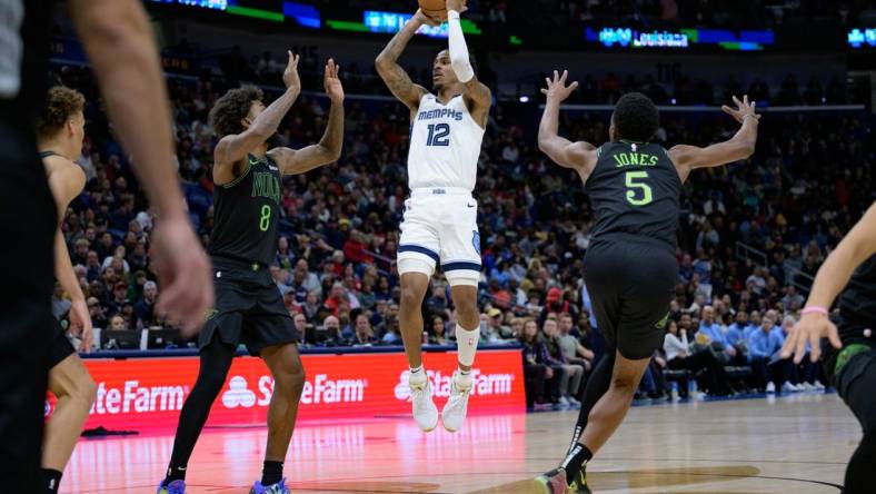 Dec 19, 2023; New Orleans, Louisiana, USA;  Memphis Grizzlies guard Ja Morant (12) shoots in between New Orleans Pelicans forwards Naji Marshall (8) and Herbert Jones (5) during the second quarter at the Smoothie King Center. Mandatory Credit: Matthew Hinton-USA TODAY Sports