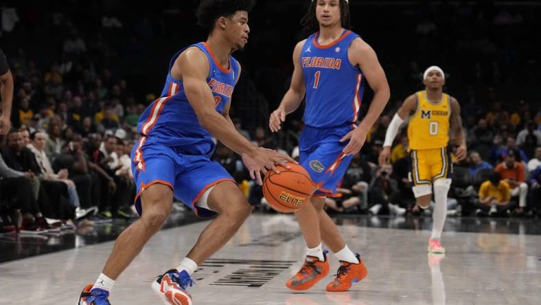 Dec 19, 2023; Charlotte, North Carolina, USA; Florida Gators guard Zyon Pullin (0) handles the ball watched by guard Walter Clayton Jr. (1) during the second half against the Michigan Wolverines at Spectrum Center. Mandatory Credit: Jim Dedmon-USA TODAY Sports