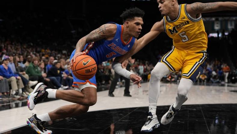 Dec 19, 2023; Charlotte, North Carolina, USA; Florida Gators guard Will Richard (5) drives to the basket against Michigan Wolverines forward Terrance Williams II (5) during the first overtime period at Spectrum Center. Mandatory Credit: Jim Dedmon-USA TODAY Sports